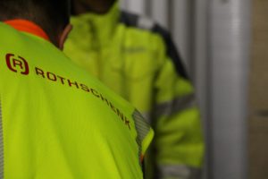 Wie is verantwoordelijk voor het beveiligen van de lading? | Diensten: Medewerkers dragen goed zichtbare vesten met Rothschenk-logo tijdens een laadsituatie.