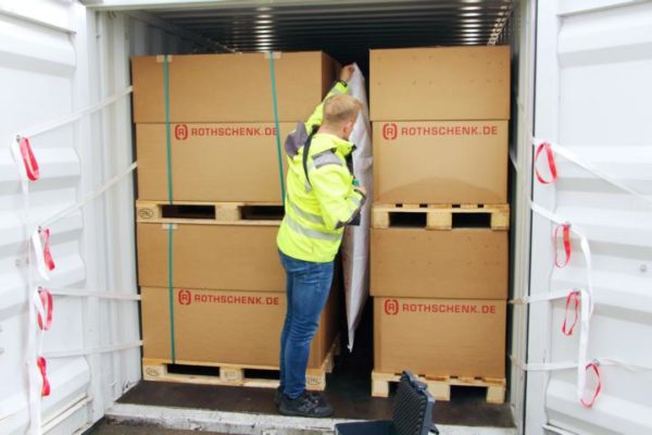 An employee of G&H GmbH Rothschenk positions a dunnage pad between two pallets in a container.
