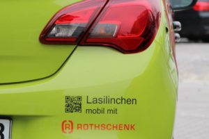 Een limoengroene auto "Lasilinchen" met het bedrijfslogo van G&H GmbH Rothschenk van achteren.