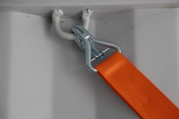 A wheel lash is secured in an eyelet in a container with a safety hook.