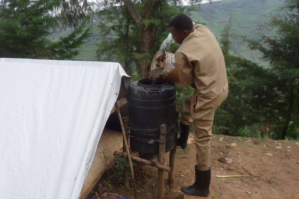 Een plaatselijke bewoner vult een emmer met bio-meststof in een mengvat.