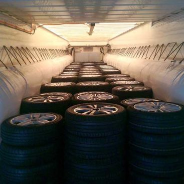 Car tires are secured in a container with two air cushions suspended lengthwise.